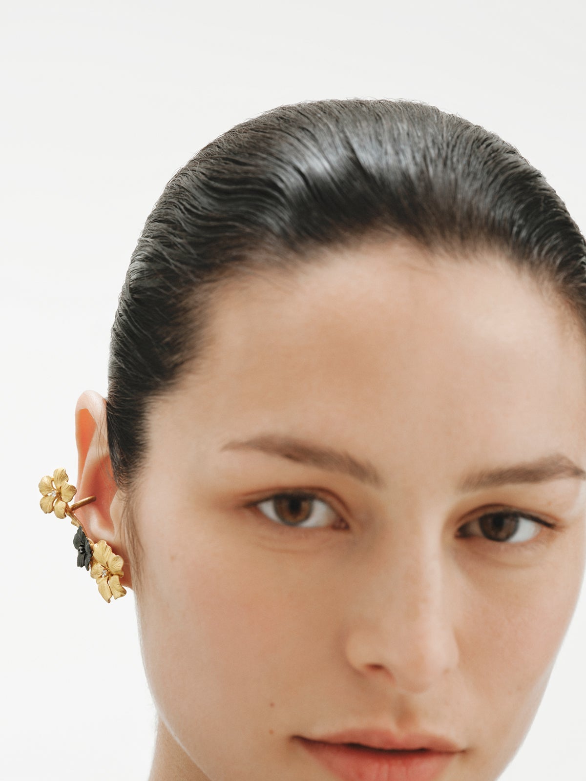 Climbing earcuff plated in yellow gold with crystals and flower motifs