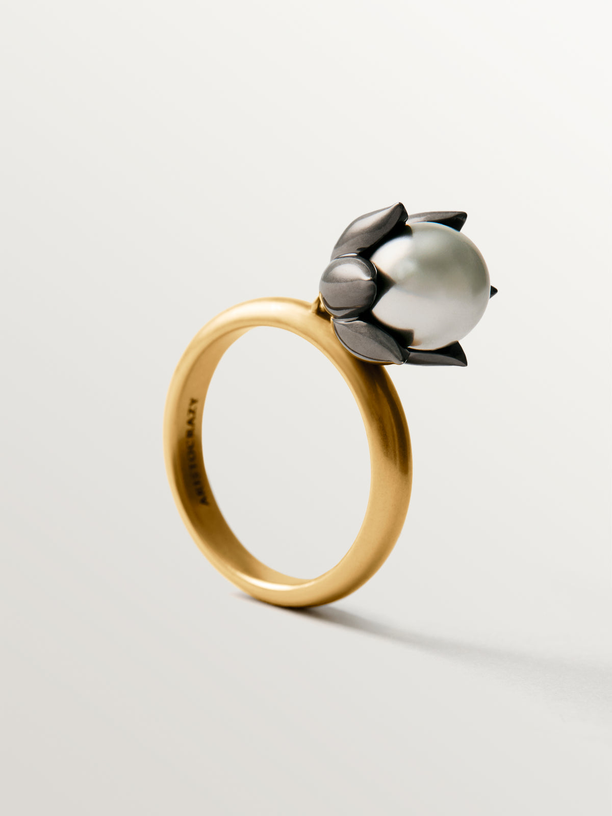 Two-tone ring plated in yellow gold with a gunmetal finish, gray pearl and flower shape