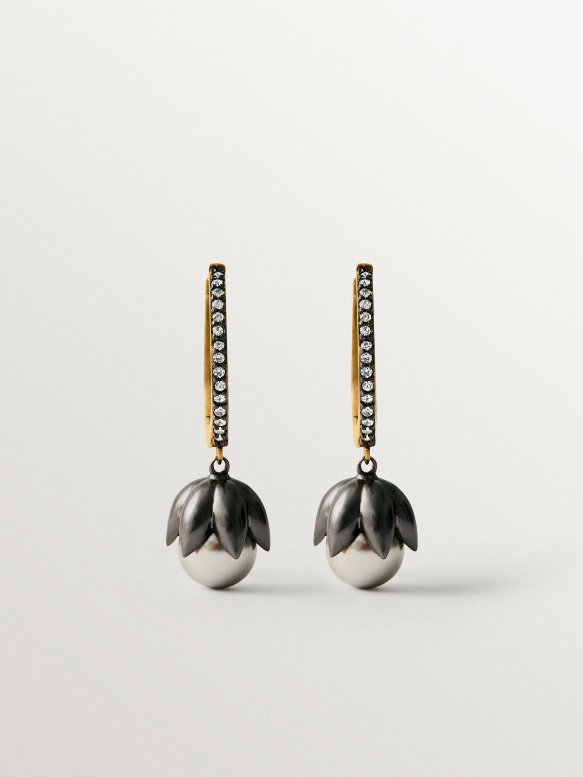 Two-tone hoop earrings plated in yellow gold with a gunmetal finish, gray pearls, crystals and flower shape