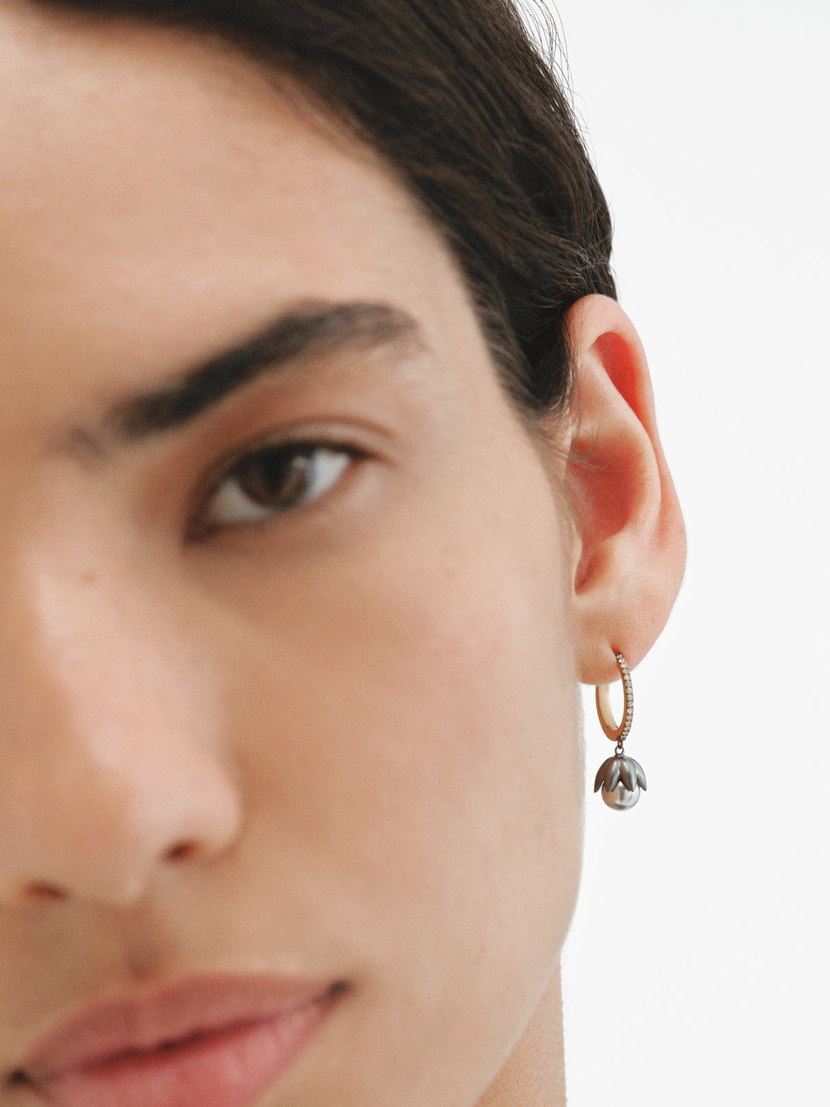 Two-tone hoop earrings plated in yellow gold with a gunmetal finish, gray pearls, crystals and flower shape