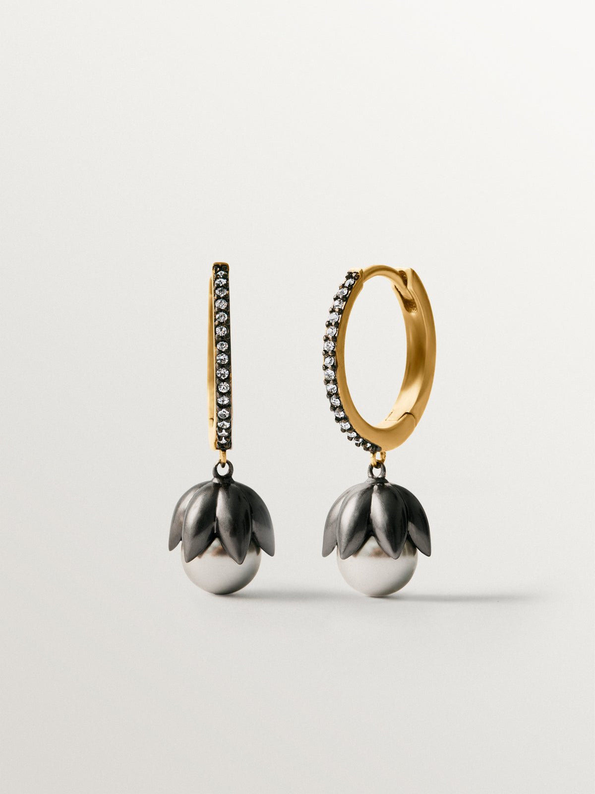 Two-tone hoop earrings plated in yellow gold with a gunmetal finish, gray pearls, crystals and flower shape