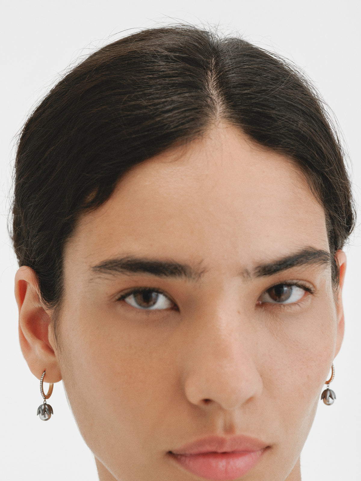 Two-tone hoop earrings plated in yellow gold with a gunmetal finish, gray pearls, crystals and flower shape