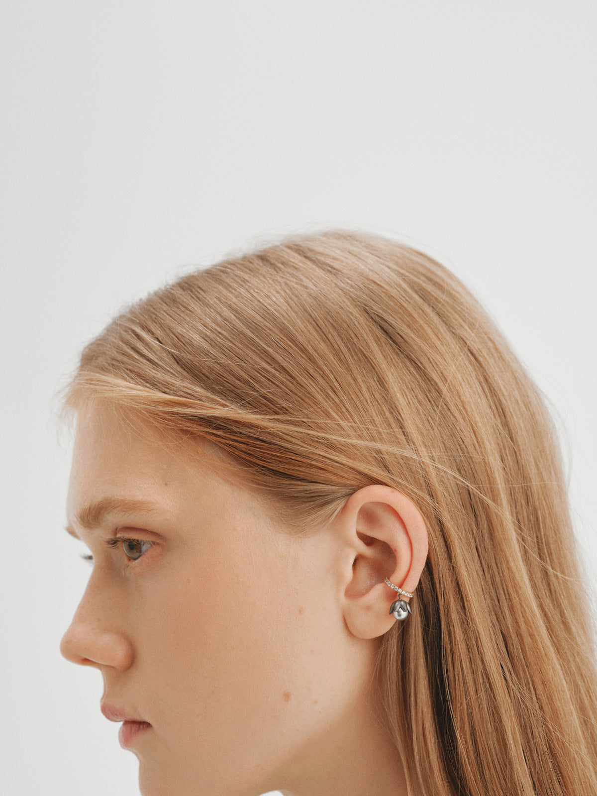 Two-tone yellow gold-plated ear cuff with gunmetal finish, white crystals and flower-shaped grey crystal