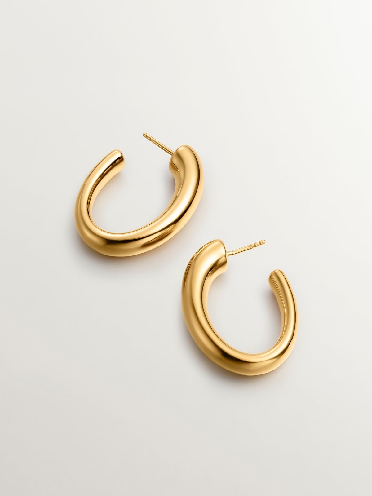 Large and thick hoop earrings made of 925 silver, bathed in 18K yellow gold, with an oval shape.