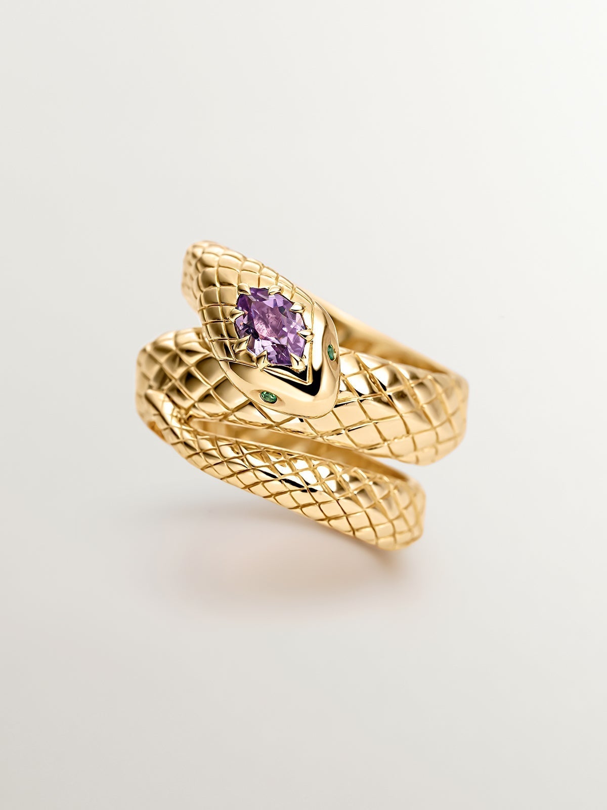 Wide 925 silver ring bathed in 18K yellow gold with a snake shape, purple amethyst and green tsavorites.