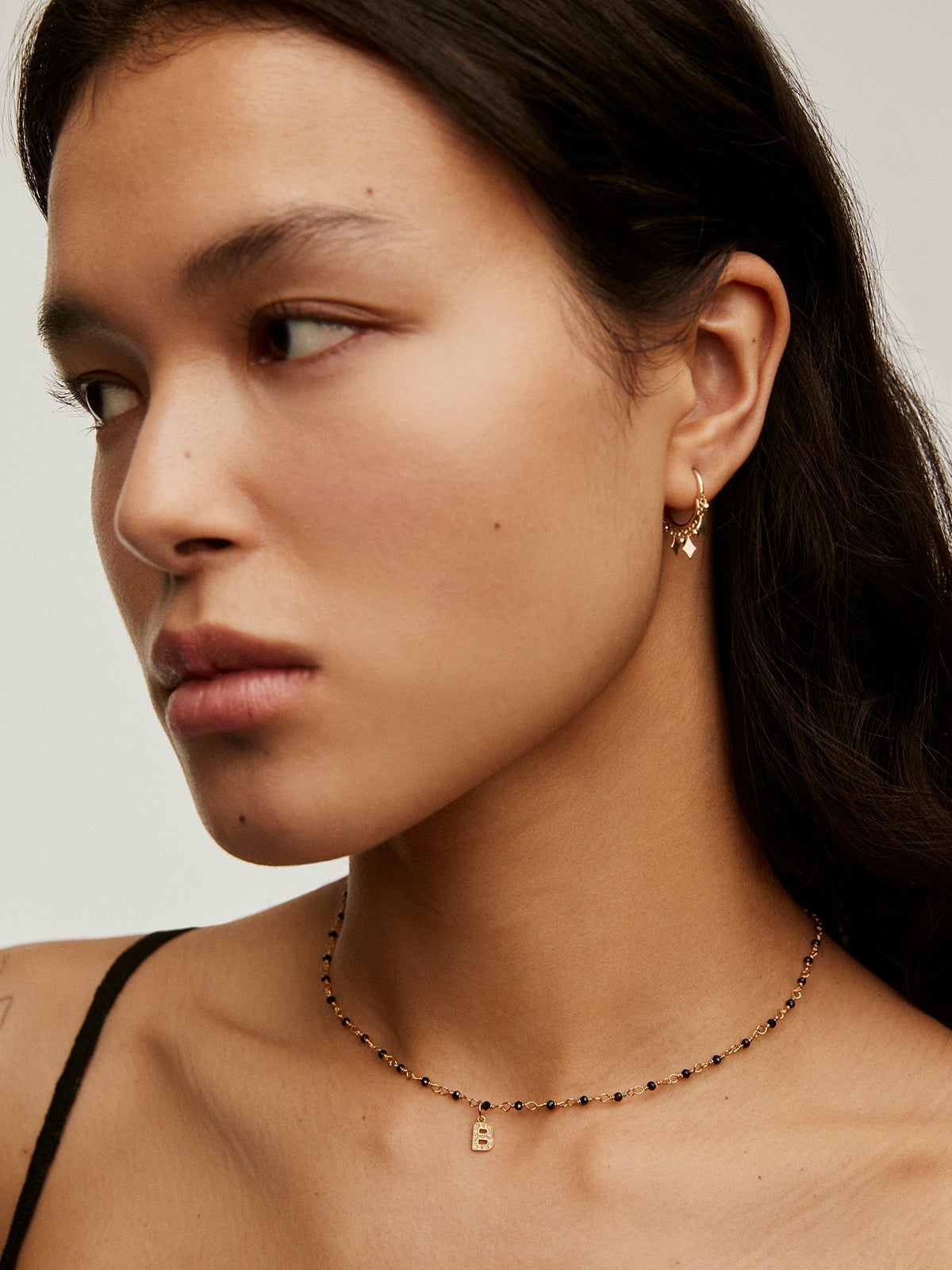 Initial B charm, made of 925 silver coated in 18K yellow gold and adorned with white topaz.
