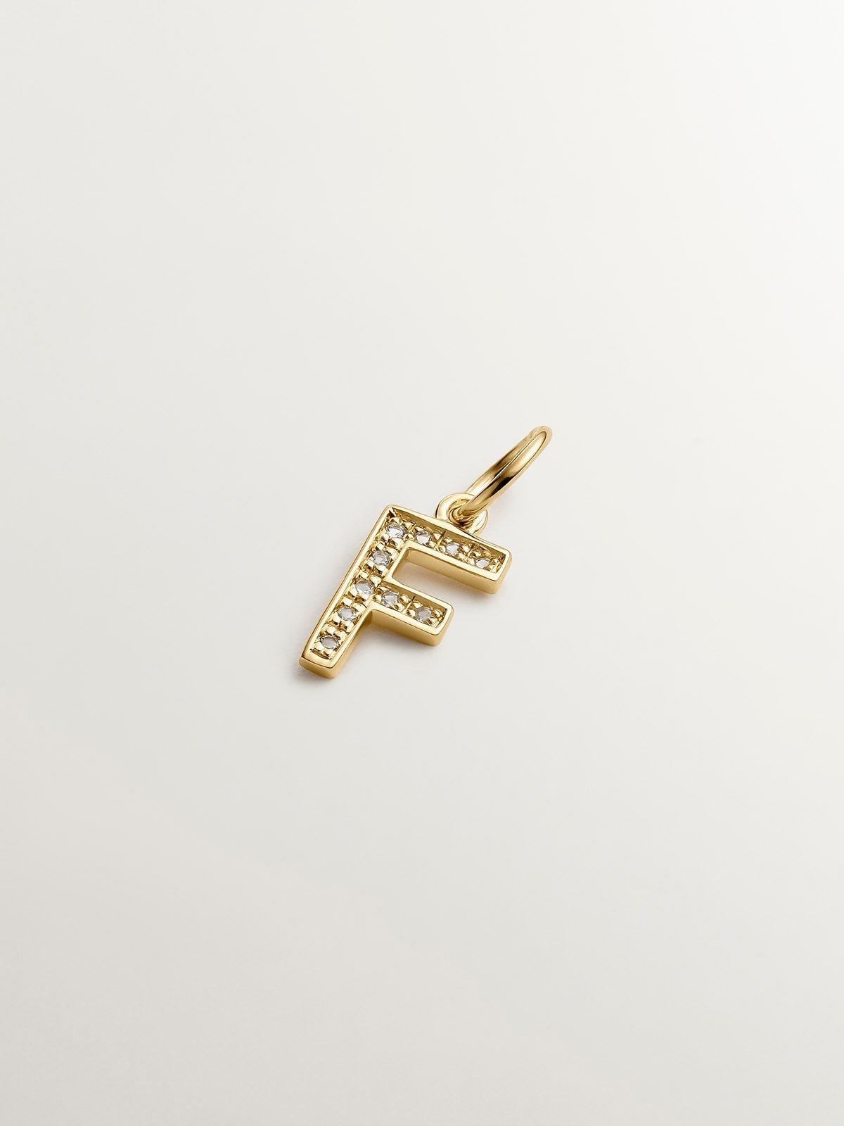 F initial charm made of 925 silver, bathed in 18K yellow gold with white topazes.