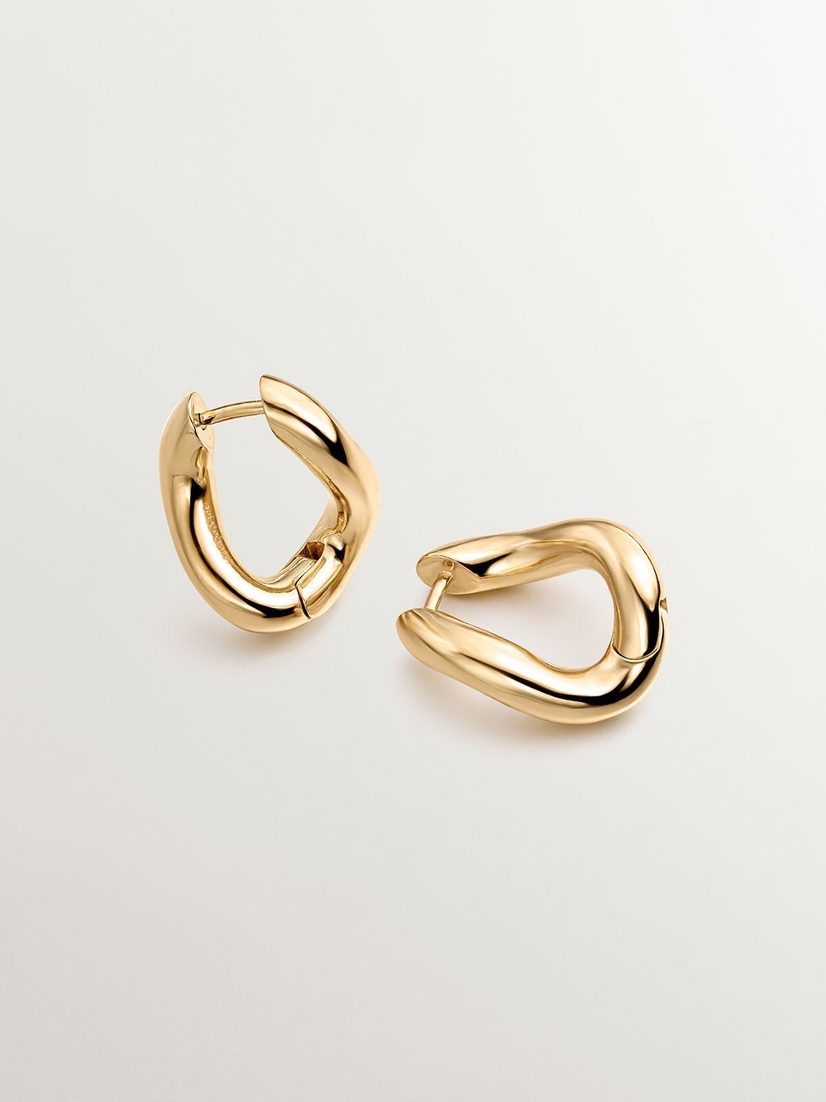 Medium thick 925 silver hoop earrings bathed in 18K yellow gold with a wavy shape.