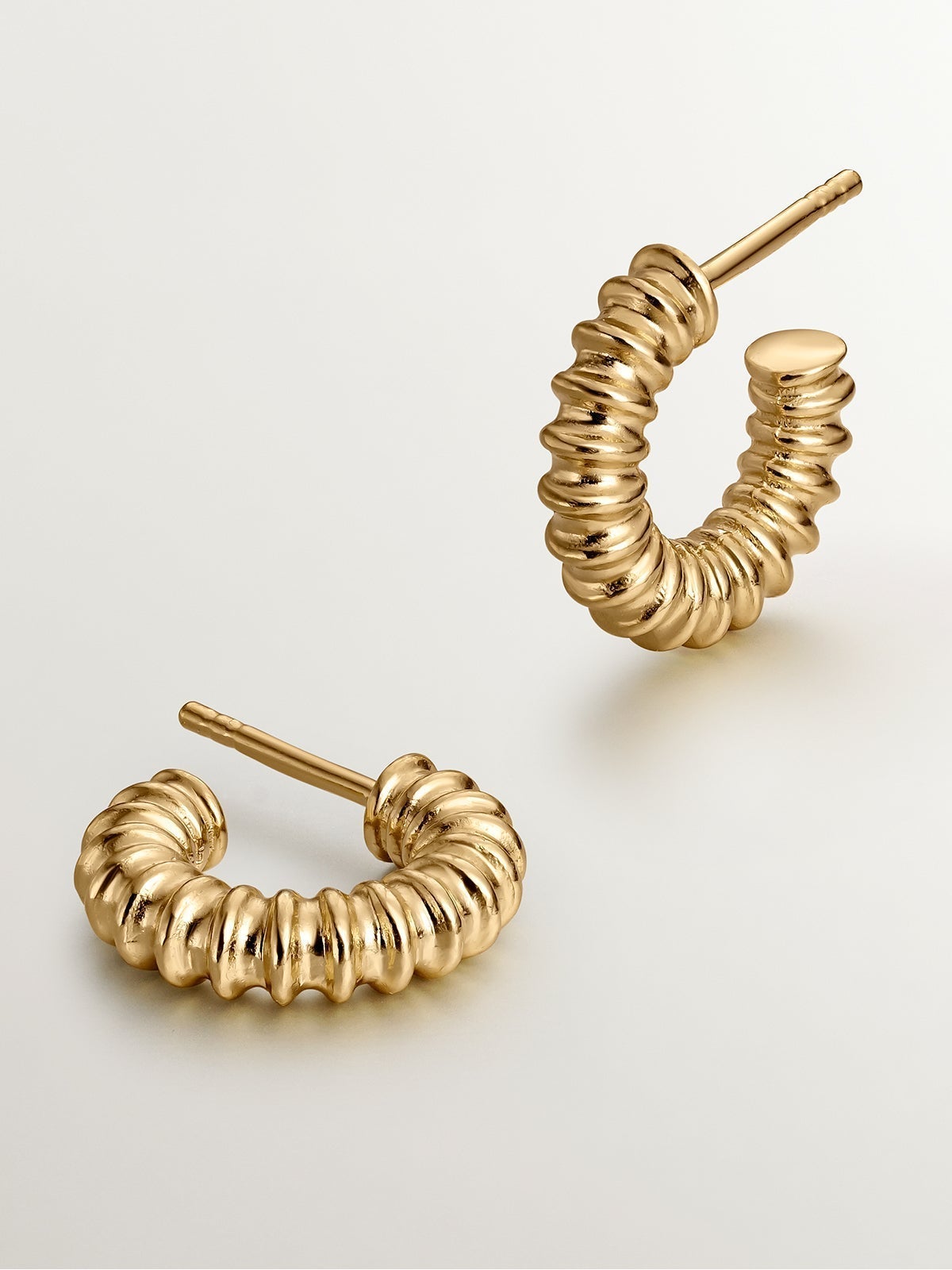 Small hoop earrings made of 925 silver plated in 18K yellow gold with an embossed finish.