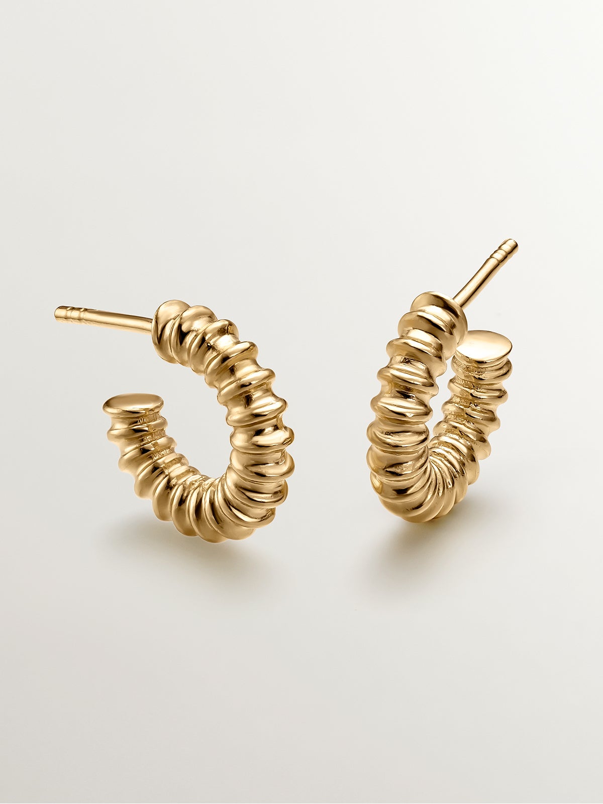 Small hoop earrings made of 925 silver plated in 18K yellow gold with an embossed finish.