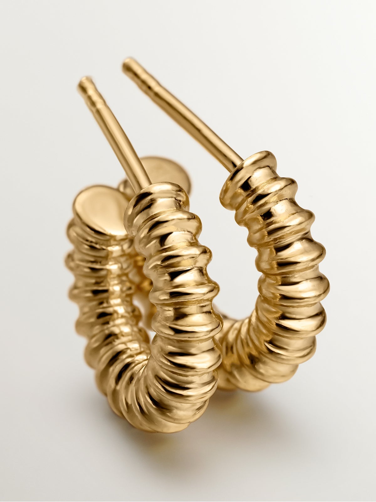 Small hoop earrings made of 925 silver plated in 18K yellow gold with an embossed finish.