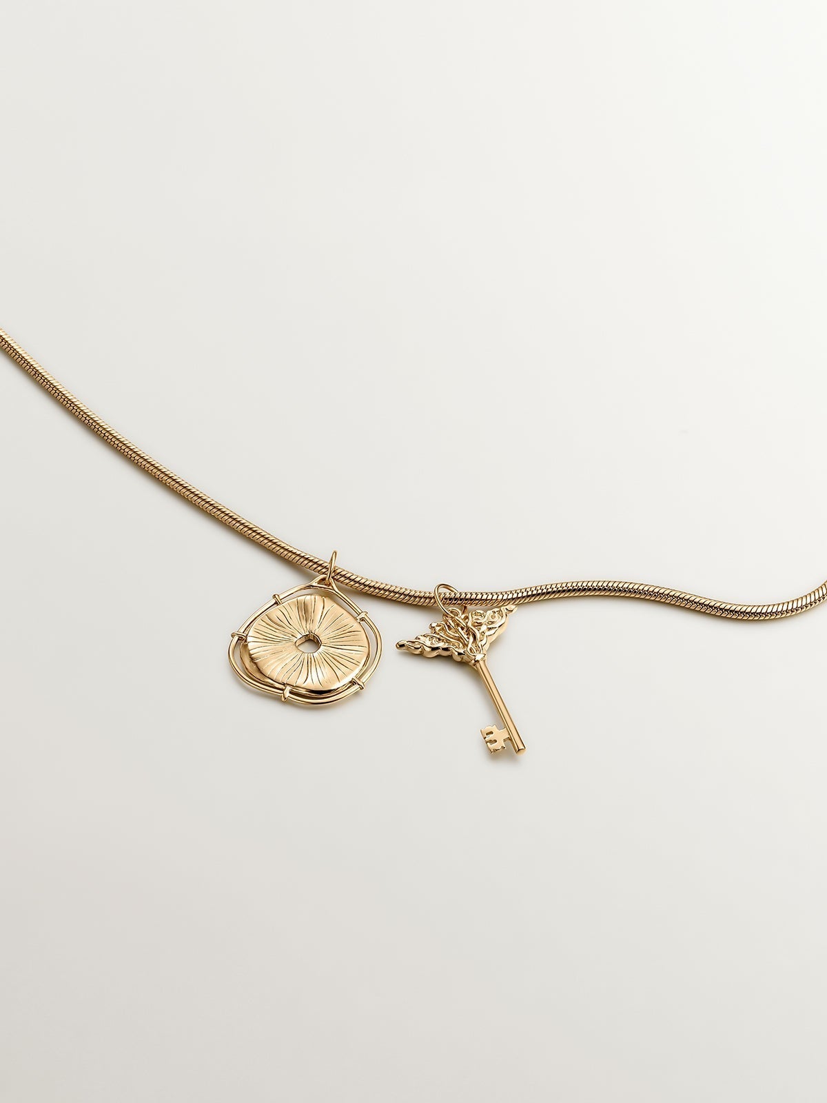 925 Silver charm, gold-plated in 18K yellow gold, with an irregular medallion shape and white topaz stones.