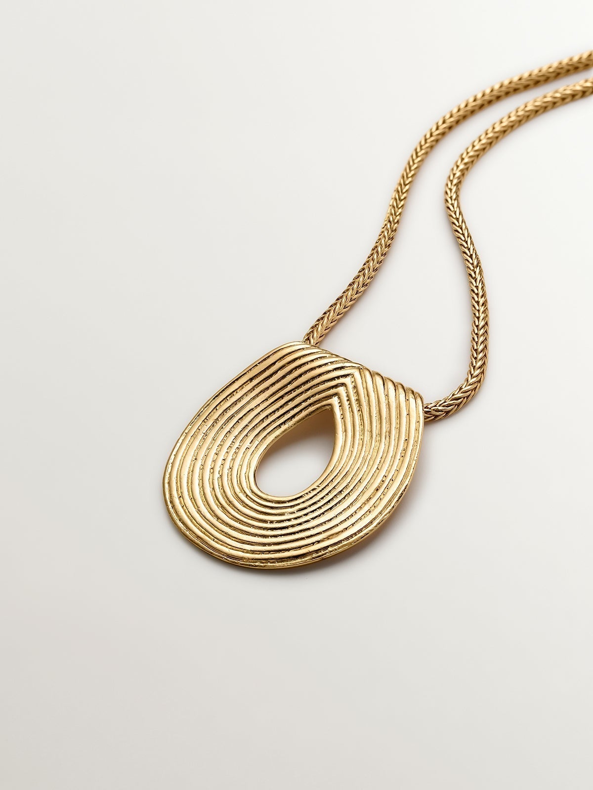 Oval pendant made of 925 silver bathed in 18K yellow gold with relief.
