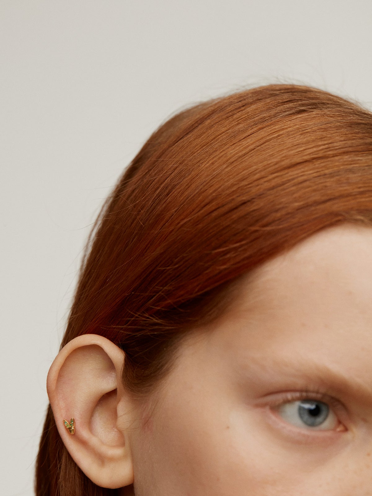 18K yellow gold piercing with emeralds and wing shape