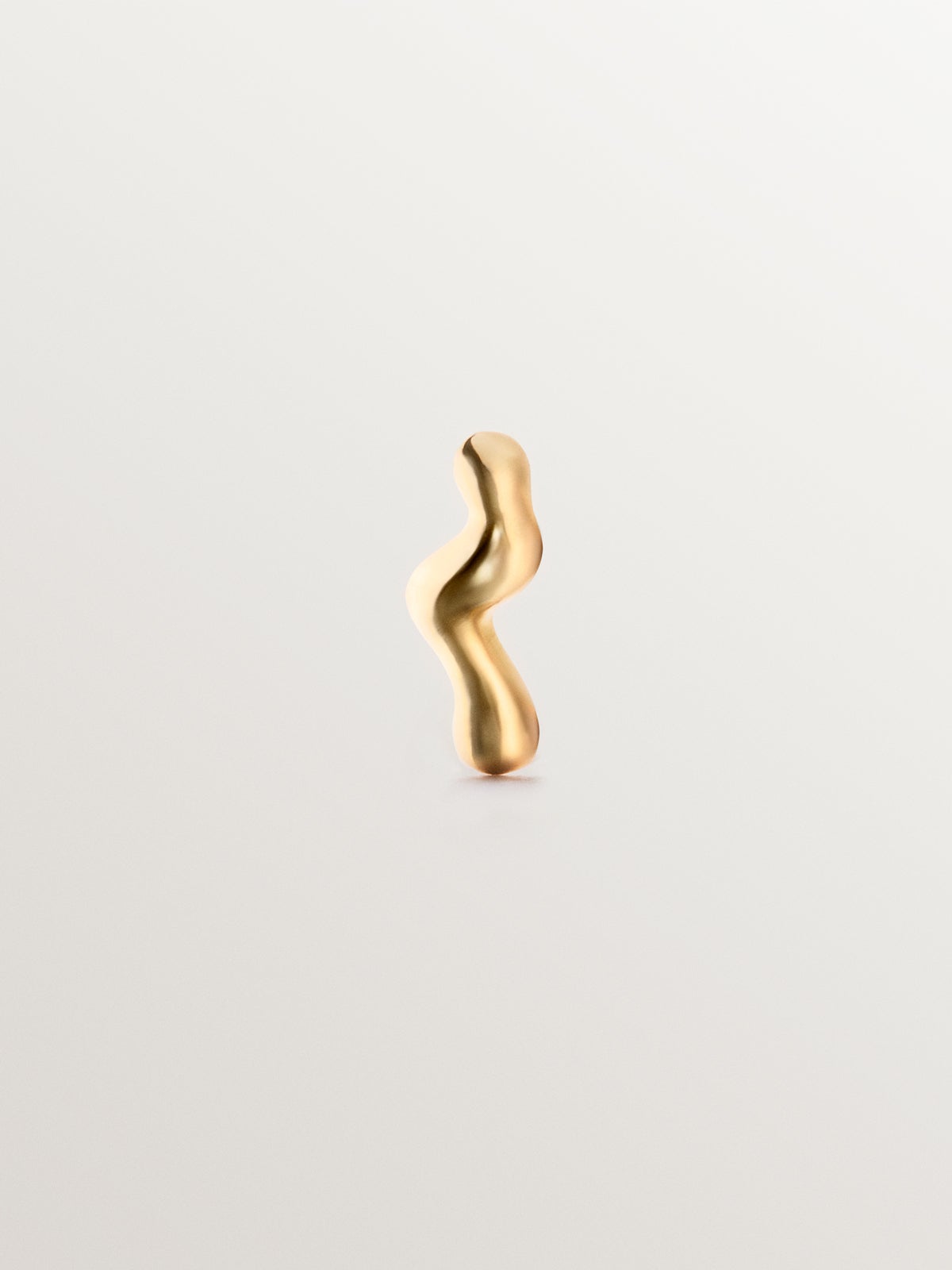 Individual 18K yellow gold piercing with an organic wave shape
